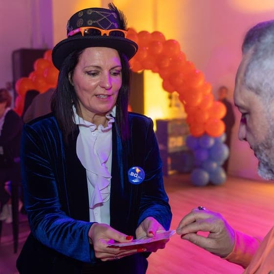 Karine tendant un jeu de cartes à un spectateur lors d’une soirée d’entreprise