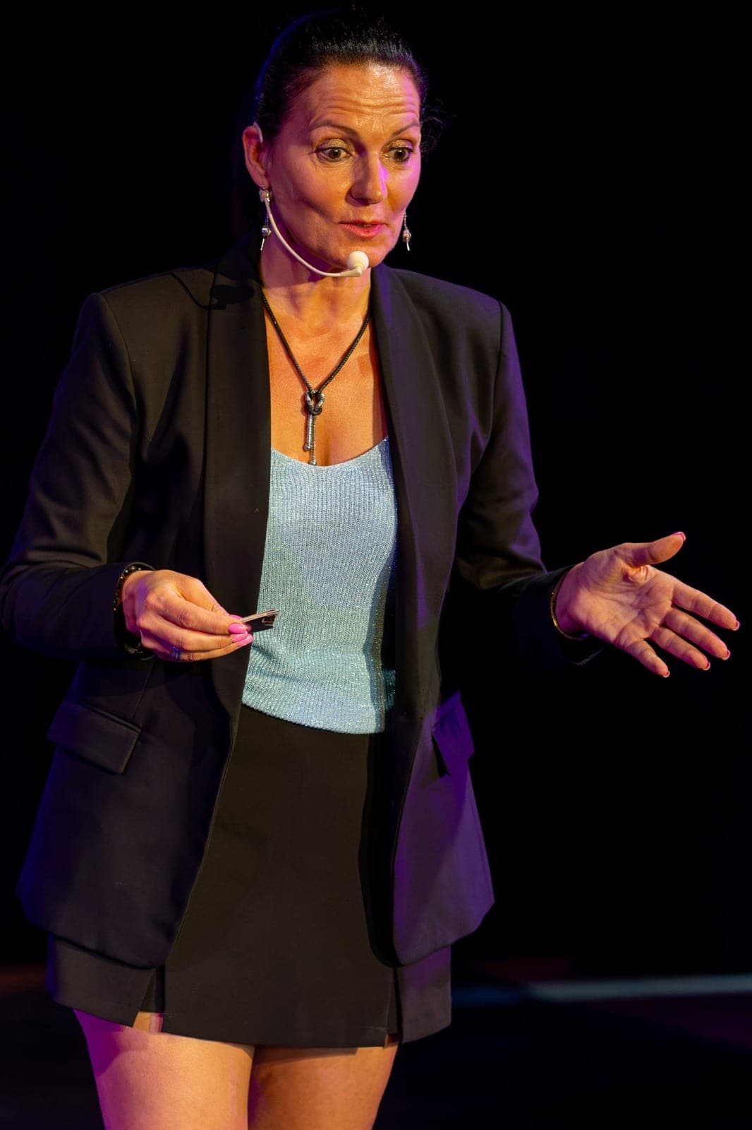 Karine expliquant un tour, une main ouverte vers le public