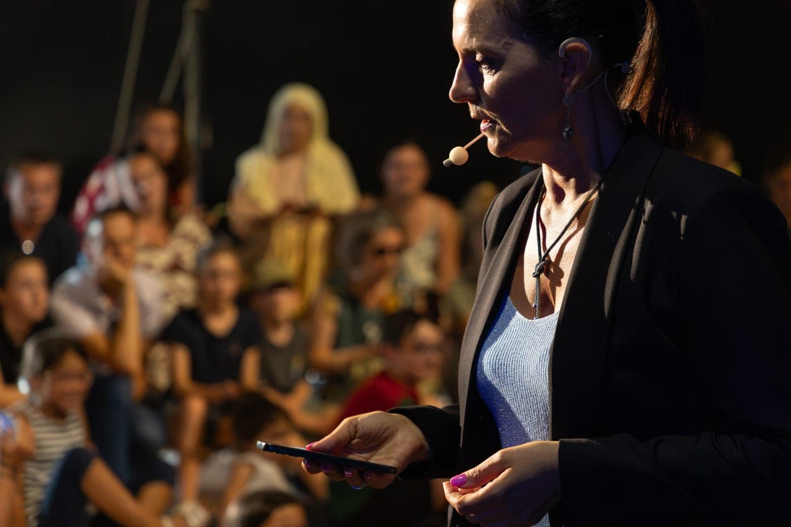 Karine près de sa malle de scène garnie de baguettes magiques colorées